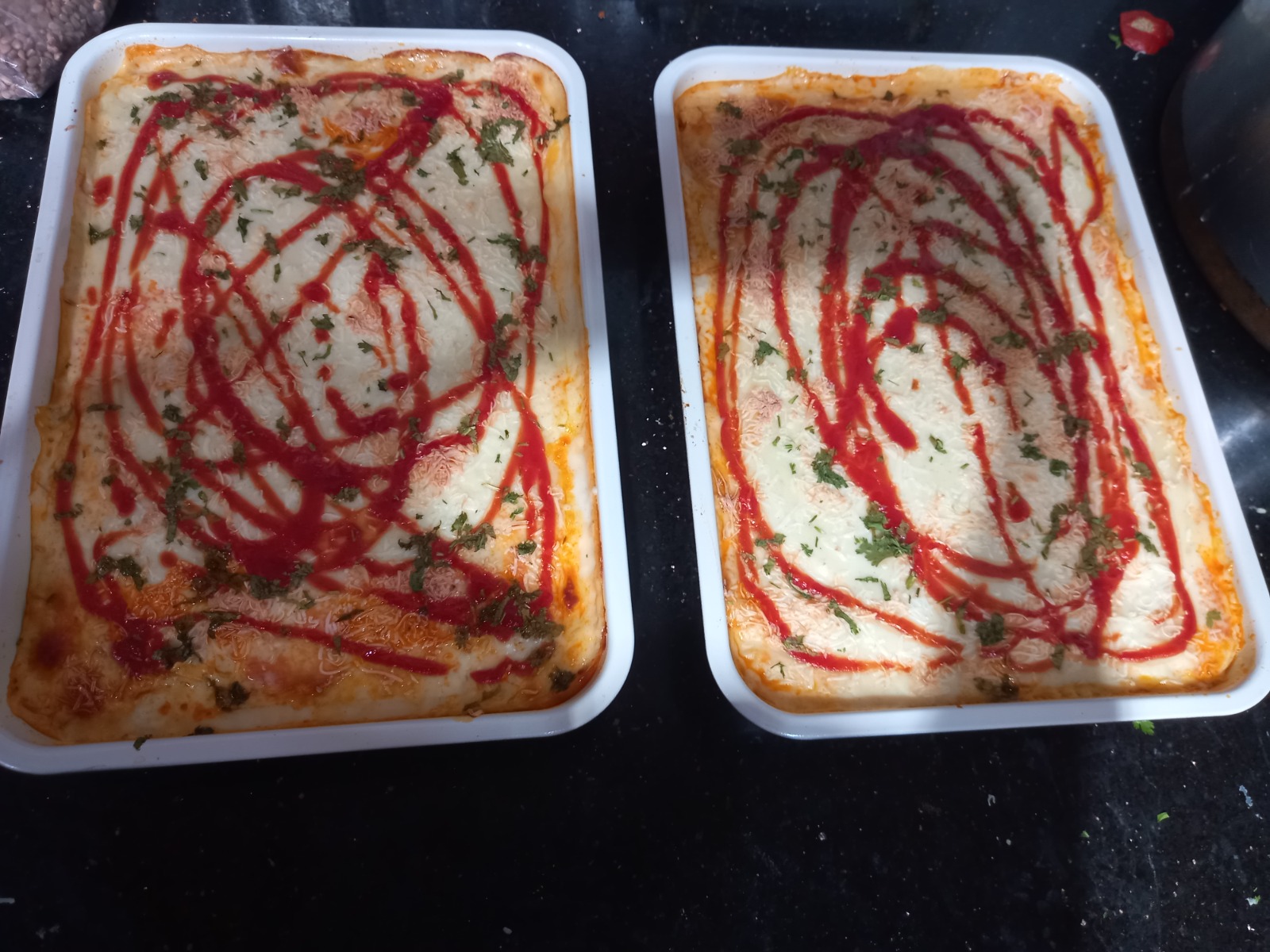Trays of baked chicken lasagna topped with cheese and sauce