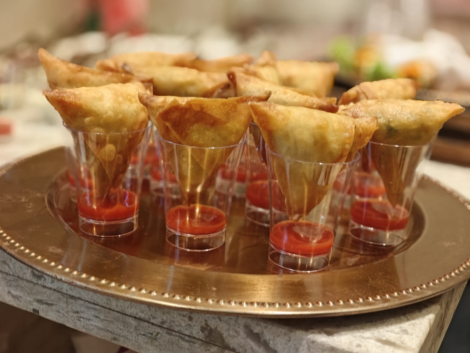 Samosas served in shot glasses with tomato sauce