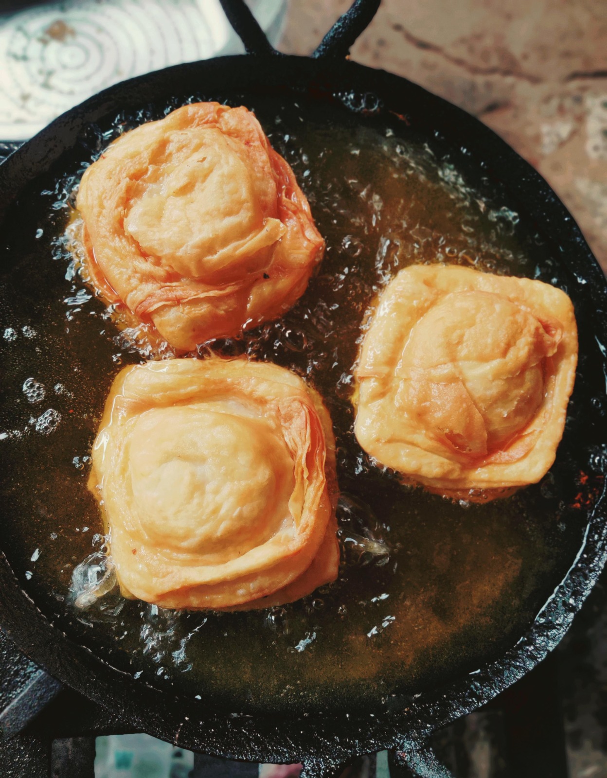 Warki samosas frying in a cast iron pan