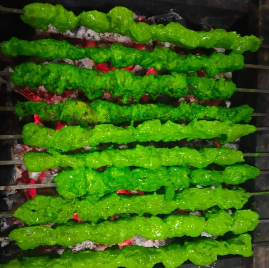 Green hariyali kababs grilling over charcoal