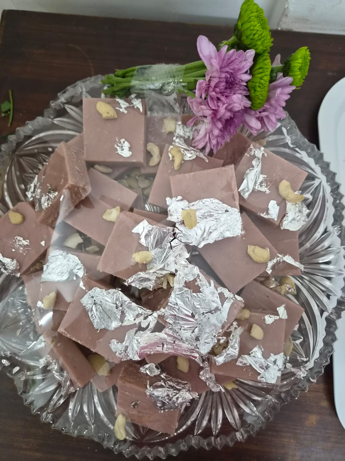 Rose coconut barfi with silver leaf and cashews on a crystal platter