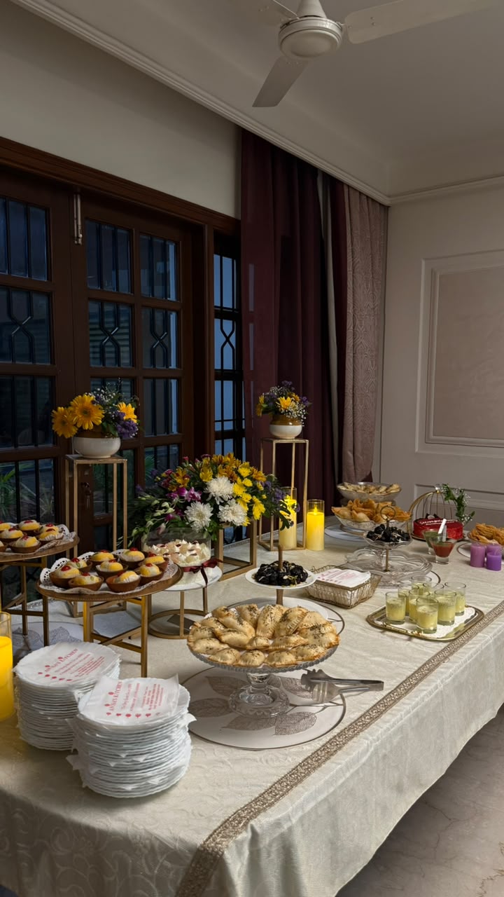 Elegant high tea dessert table with flowers, samosas and drinks