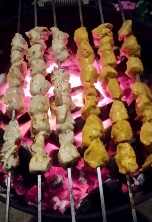 Malai and zafrani chicken tikka skewers over glowing coals