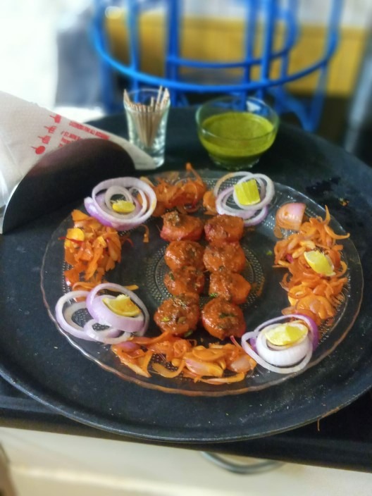 Seekh kababs plated with onion rings, salad and green chutney