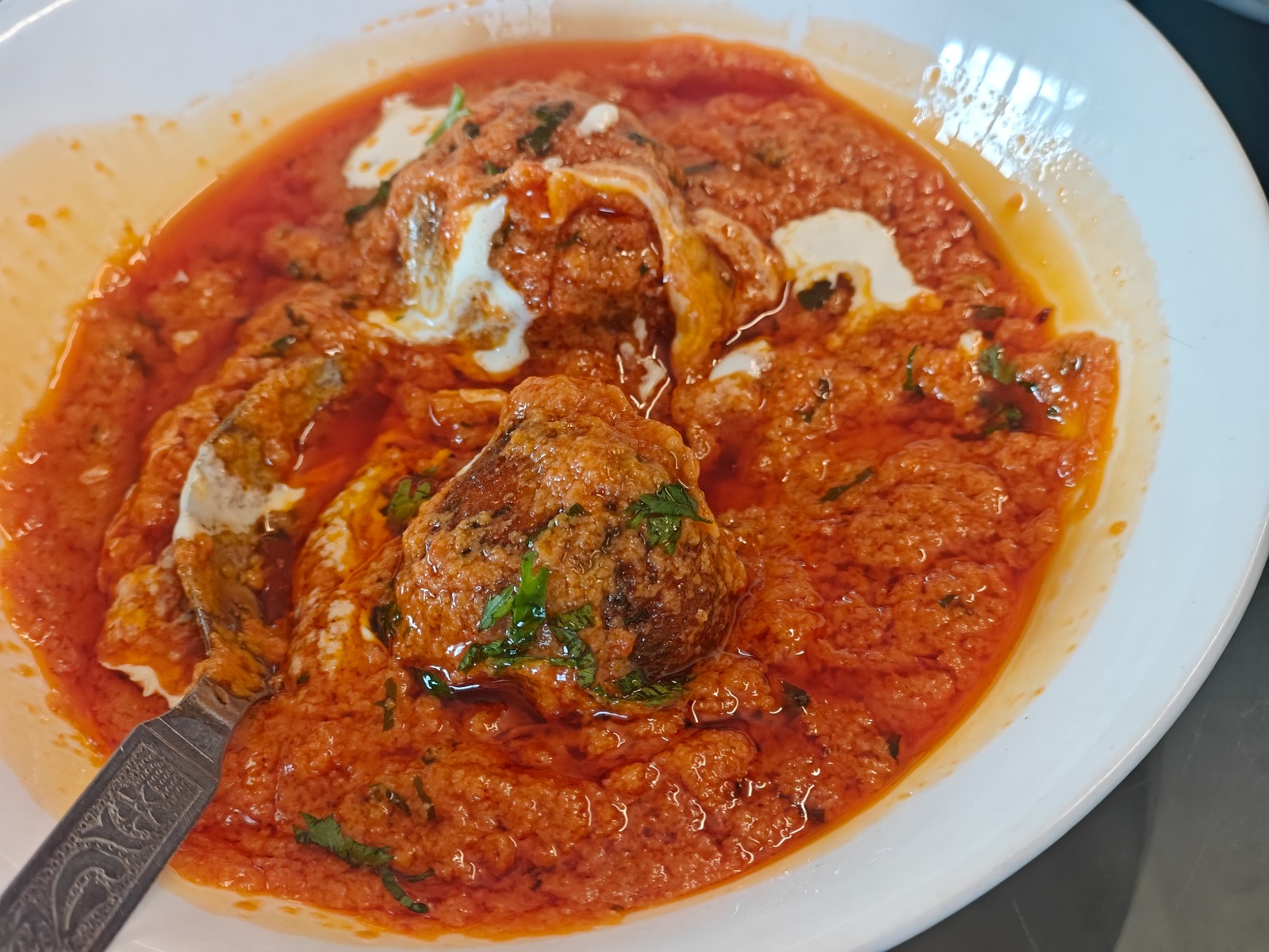 Kofta balls in a rich red curry topped with cream and coriander